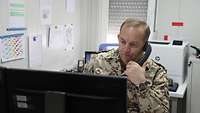 Einen Teil seines Tages muss Oberst Wellbrink am Telefon verbringen um mit seinen Soldaten zu sprechen Ein deutscher Soldat im Einsatz sitzt in seinem Büro und telefoniert während er auf einen Computerbildschirm schaut