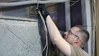 Ein Soldat überprüft die Kabelführung an einem Gerät