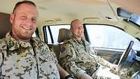 Zwei Soldaten sitzen im Innenraum eines Fahrzeugs