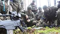 Eine Gruppe Soldaten versammelt sich im Wald und betrachtet eine Karte