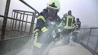Mehrere Menschen in Feuerwehrschutzanzügen mit Helmen und Atemmasken.