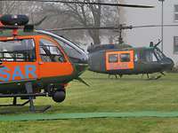 LUH SAR und Bell UH-1D (r.) Zwei Hubschrauber stehen leicht versetzt hintereinander auf einer Wiese.