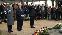 Ein Gruppe von Soldaten und Zivilisten steht vor kleinen Särgen