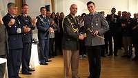 Ein argentinischer Soldat gratuliert einem deutschen Soldaten, der einen Säbel hält.