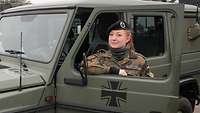 Stabsgefreiter Jennifer Staffeld Eine Soldatin steht an der geöffneten Seitentür eines Militärjeeps und schaut durch das Fenster..