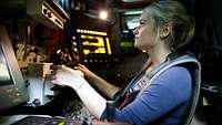 A woman is sitting at a vehicle workplace surrounded by many electronic devices
