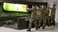 Vier Soldaten zielen auf die Projektionswand eines Schießsimulators.