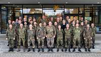 Etwa 40 Soldaten stehen auf einer Treppe in vier Reihen vor der Glasfront eines Gebäudes.