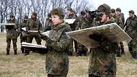 Eine Gruppe von Soldaten stehen mit Karte, Kompass und Fernrohr auf einem Feld.