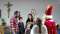 Der Heilige Nikolaus mit seinem Engel beschenkt eine Familie