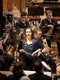 Eine Sängerin im schwarzen Kleid vor einem Orchester.