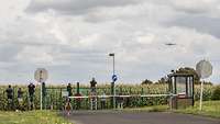 „Spotter“ beim Fotografieren einer Boeing 707 Eine Boeing 707 im Landeanflug auf Nörvenich. Am Zaun mehrere Menschen auf Leitern.
