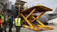 Ein Highloader hebt hydraulisch Menschen und Tragen mit Patienten auf Höhe des Frachttors des A310 an.
