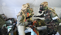 Soldaten mit ABC-Masken versorgen Verletzten