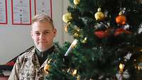 Ein Soldat steht neben einem Weihnachtsbaum