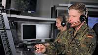 Zwei Soldaten mit Headsets vor Computern.