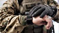 Ein Soldat schaut auf seine Armbanduhr.