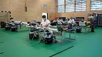Blutspender liegen auf Tragen zur Blutspende in der Sporthalle
