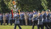 Musiker in Uniform marschieren auf einer Wiese auf, Soldaten sind angetreten.