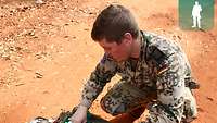 Ein Soldat kniet vor seinem geöffneten Sanitätsrucksack