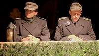 Eine Soldatin und ein Soldat in Gebirgsjägeruniform sitzen an einem Tisch.