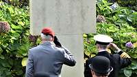 Ein Soldat legt zusammen mit Militärs und Zivilisten der Insel Guernsey einen Kranz nieder.