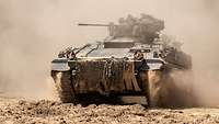 Ein Panzer in voller Fahrt in staubiger Erde