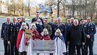 Gruppenbild mit Soldaten und den Sternsingern mit ihrem Scheck. Im Hintergrund ein Militärflugzeug