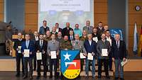 Gruppenbild: Die Ausgezeichneten stehen mit ihren Urkunden und dem Wappen der Mission auf der Bühne.