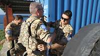 Ein deutscher UN-Soldat hilft einem anderen Soldaten beim Anlegen der Schutzweste