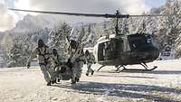Vier Soldaten tragen die Trage mit dem Verletzten vom Hubschrauber weg.