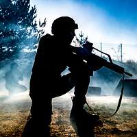 Im Gegenlicht: Zwei Soldaten hocken und sichern mit Waffen im Anschlag die Umgebung.