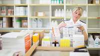 Apothekerin steht in Lager und notiert etwas