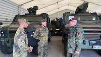 Der Generalinspekteur ist im Gespräch mit zwei Soldaten, die ihm die Gefechtsfahrzeuge vorstellen.