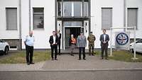 Gruppenfoto von sieben Menschen, die vor einem Gebäudeeingang stehen