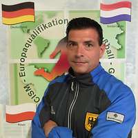 Ein Soldat in einem Sportanzug steht vor einem Plakat.