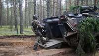 Eine Soldatin steigt über die Heckklappe in den Schützenpanzer Marder ein