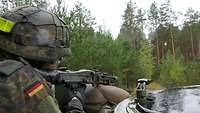 Eine Soldatin mit Maschinengewehr sichert über die Bordwand des Schützenpanzers Marder