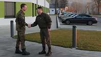 Vor dem Stabsgebäude begrüßen sich zwei Soldaten mit Handschlag.