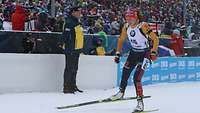 Biathletin fährt an einer Bande vorbei.