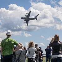 Besucher beobachten ein Transportflugzeug vom Typ A400M am Himmel