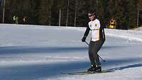 Mann mit einen Arm auf Skiern.