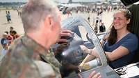 Ein Soldat spricht mit einer Frau, die im Cockpit eines Flugzeuges sitzt