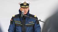 Männliche Person in Marineuniform hinter Rednerpult