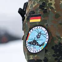 Der Soldatenärmel mit dem Patch Arctic Trial, dahinter verschwommen ein Hubschrauber.
