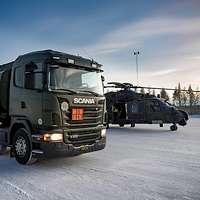 Ein Hubschrauber und ein Tankfahrzeug stehen auf einer verschneiten Landebahn.