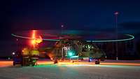 Hubschrauber beleuchtet im Dunkeln. Lichter am Ende der Rotorblätter markieren einen grünen Kreis.