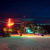 Hubschrauber beleuchtet im Dunkeln. Lichter am Ende der Rotorblätter markieren einen grünen Kreis.