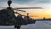 Stimmungsaufnahme im Morgengrauen. Zwei Hubschrauber stehen im Licht der aufgehenden Sonne.