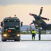 Ein Tankfahrzeug steht neben einem Hubschrauber. Beide sind verbunden mit einem Kraftstoffschlauch.